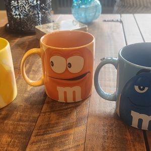 Set of three glass M&M coffee mugs. Orange, Blue& Yellow.